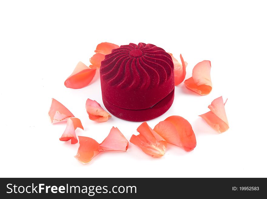 Closed box and lying next to rose petals on white background
