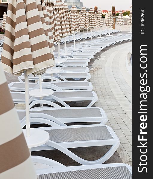 Swimming pool area of hotel with umbrella and beach chair .