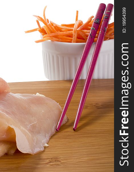 Raw chicken breast in a white plate and sliced carrots in a white plate. Raw chicken breast in a white plate and sliced carrots in a white plate.