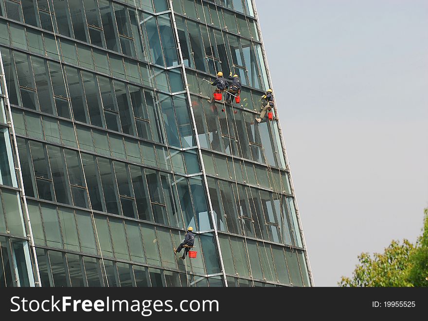 Building workers cleaning building's window glass. Building workers cleaning building's window glass.