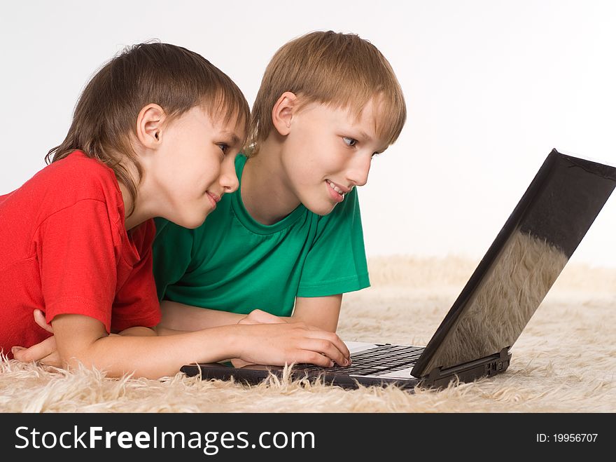 Two brothers playing at laptop on a carpet