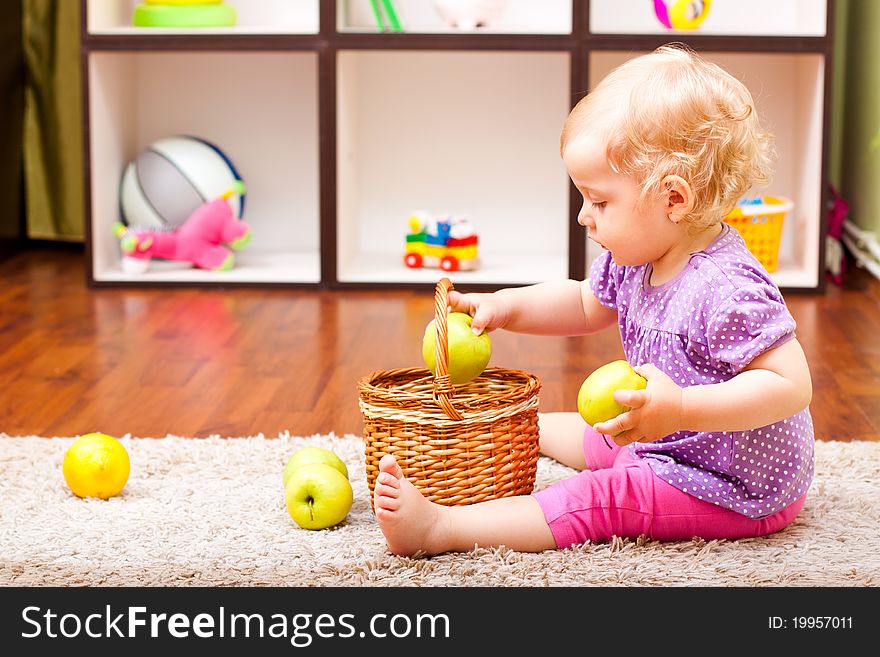 Little girl playing with apple and lemons in her room