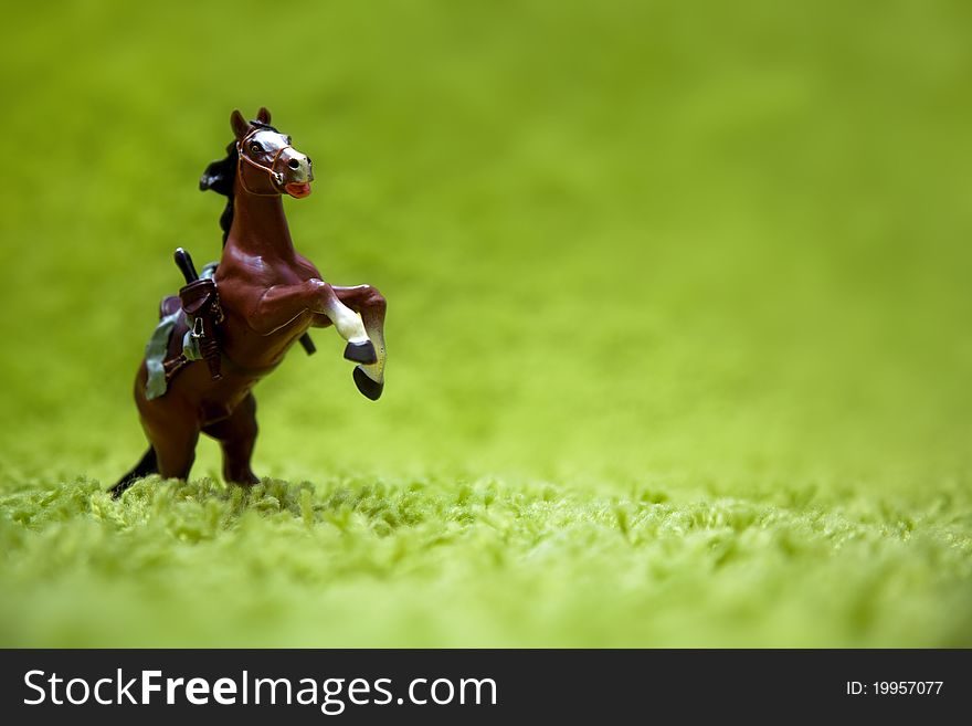 Miniature toy horse in running posture on a carpet like grass. Miniature toy horse in running posture on a carpet like grass