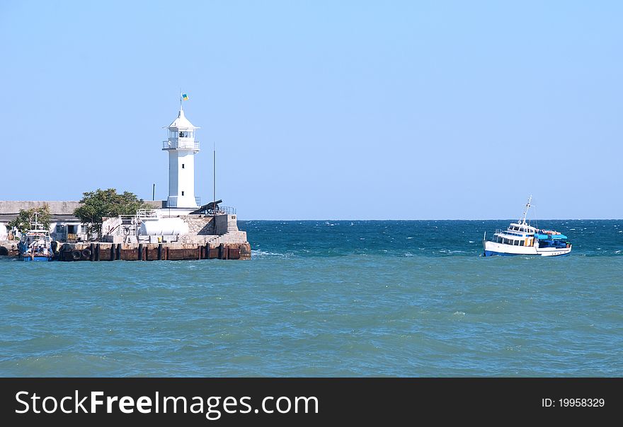 Small beacon in a sea gulf and a boat in the sea. Small beacon in a sea gulf and a boat in the sea