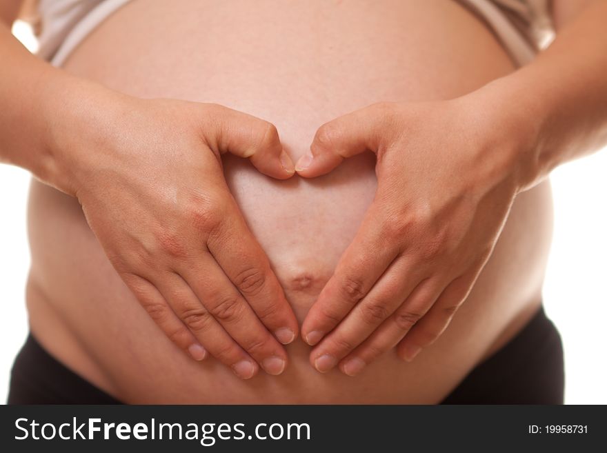 Woman's belly in 9th month of pregnancy on a white background. Hands form hart on the belly. Woman's belly in 9th month of pregnancy on a white background. Hands form hart on the belly