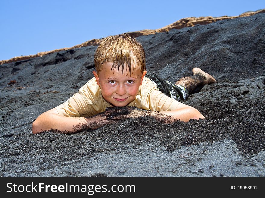 Boy has fun lying in the  black beach