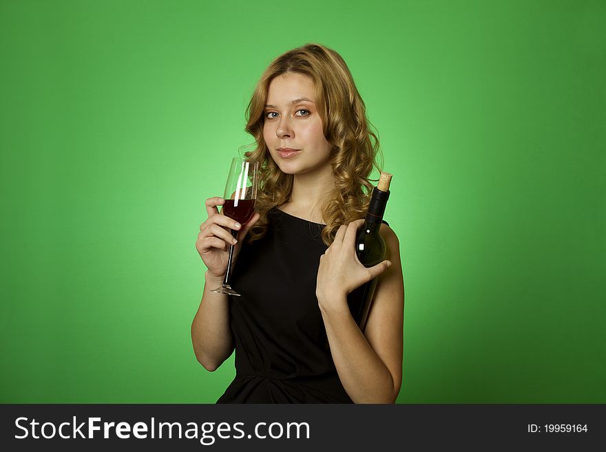 Close-up of an attractive woman on a green background in one hand and bottle in another glass of red wine. Close-up of an attractive woman on a green background in one hand and bottle in another glass of red wine