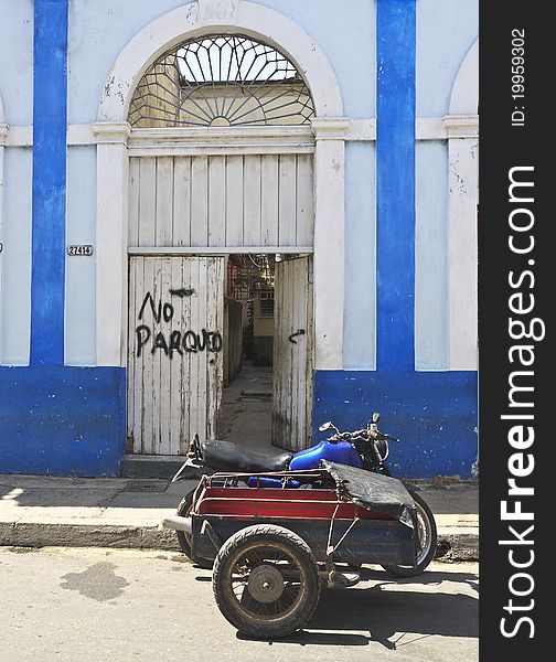 Old motorbike in front of door with sign NO PARKING