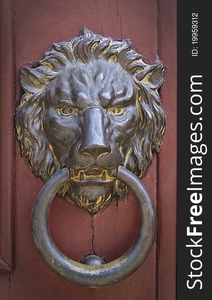 Vignette image of brass doorknocker in the shape of ferocious lion