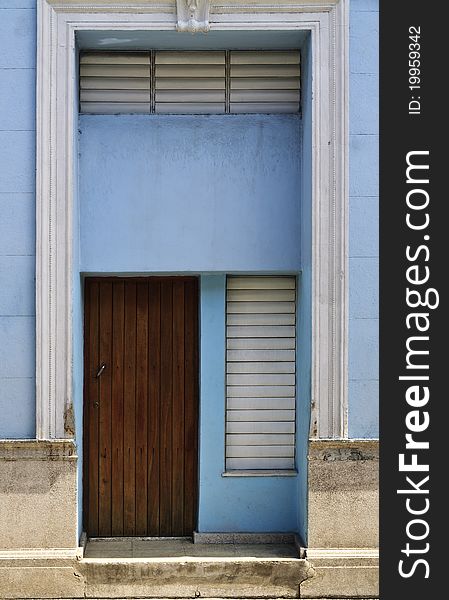 Porch with brown wooden door in blue wall