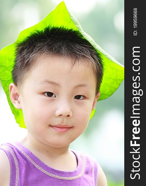 The portrait of an Asian boy with green lotus cap. The portrait of an Asian boy with green lotus cap