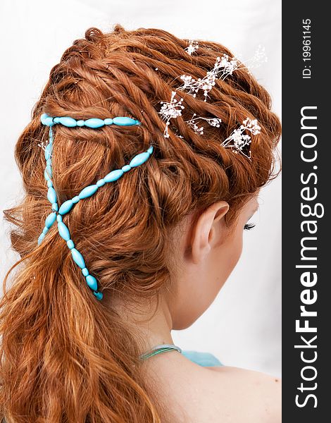 Hairdress of the red-haired girl with blue ornaments