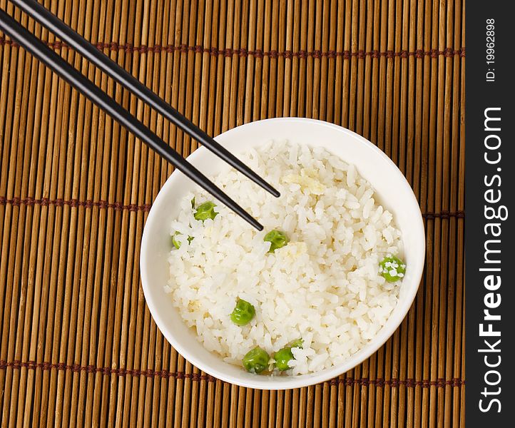 A bowl of egg fried rice with a pair of chopsticks in shoot