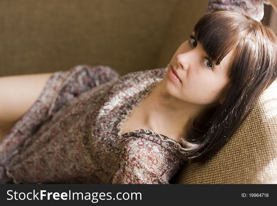 The girl in summer dress on a couch.