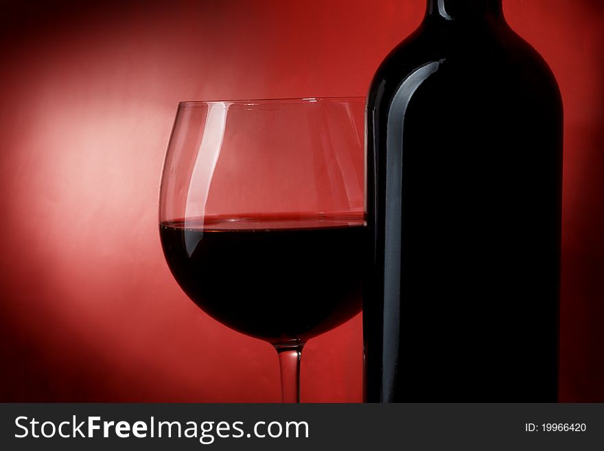 Bottle and glass of wine on a red background