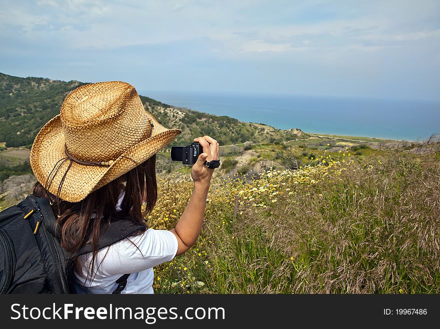 Young woman with backpack taking photo of a great landscape