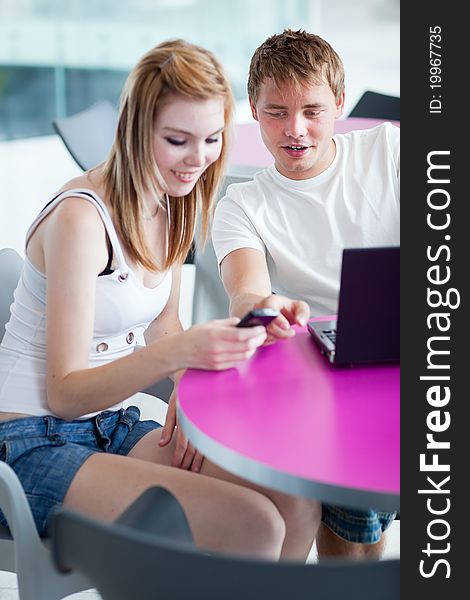 Two college students having fun studying together, using a laptop computer (shallow DOF, color toned image)