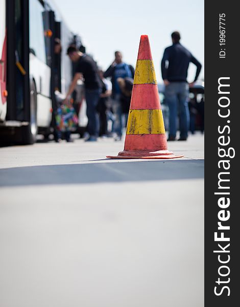 Safety cone at the aerodrome of an airport (with passengers getting on a shuttle bus in the background)