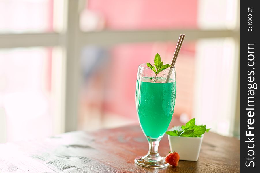 Photo of delicious mint cocktail on wooden table illuminated by daylight