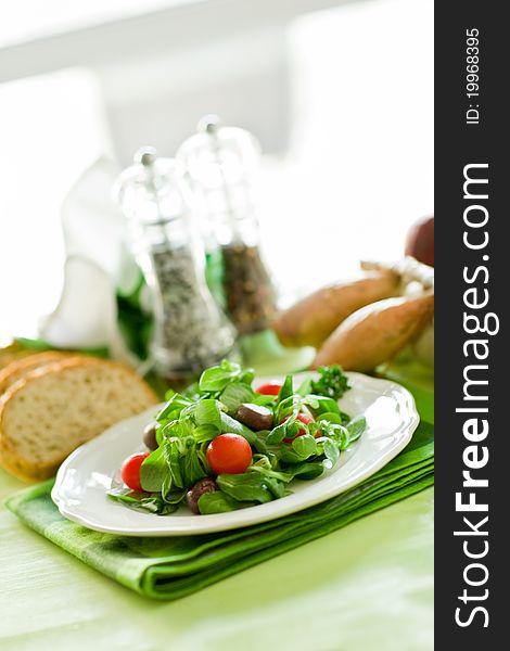 Delicious vegetarian salad on green wooden table illuminated by day light