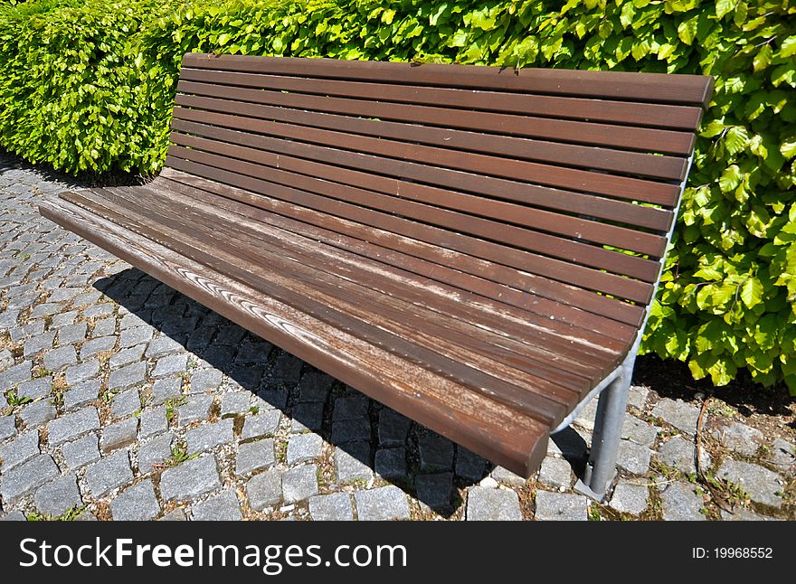 Wooden bench in front of bush