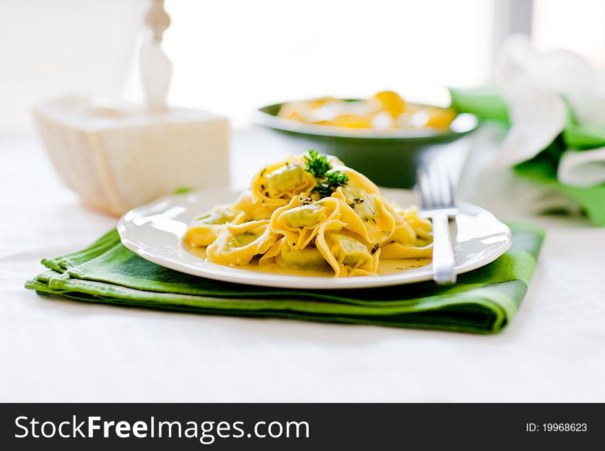 Delicious italian fresh tortellini with butter and sage on green wooden table