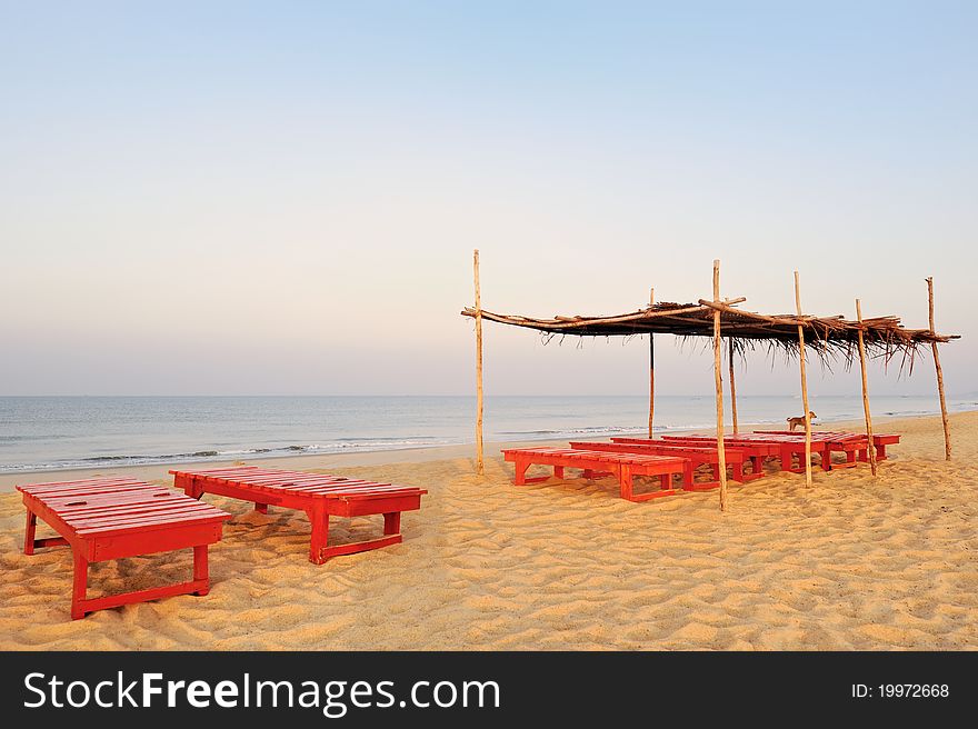 Exotic lean-to of palm leaves and red deck-chairs on tropical beach. Exotic lean-to of palm leaves and red deck-chairs on tropical beach