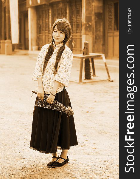 Chinese girl in traditional dress standing on Chinese ancient street.