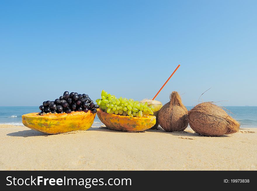 Papaya, coconut, nut and grapes on the sand. Papaya, coconut, nut and grapes on the sand