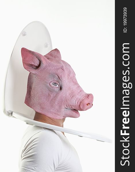 Man with a pig-mask puts his head through a toilet seat. Man with a pig-mask puts his head through a toilet seat