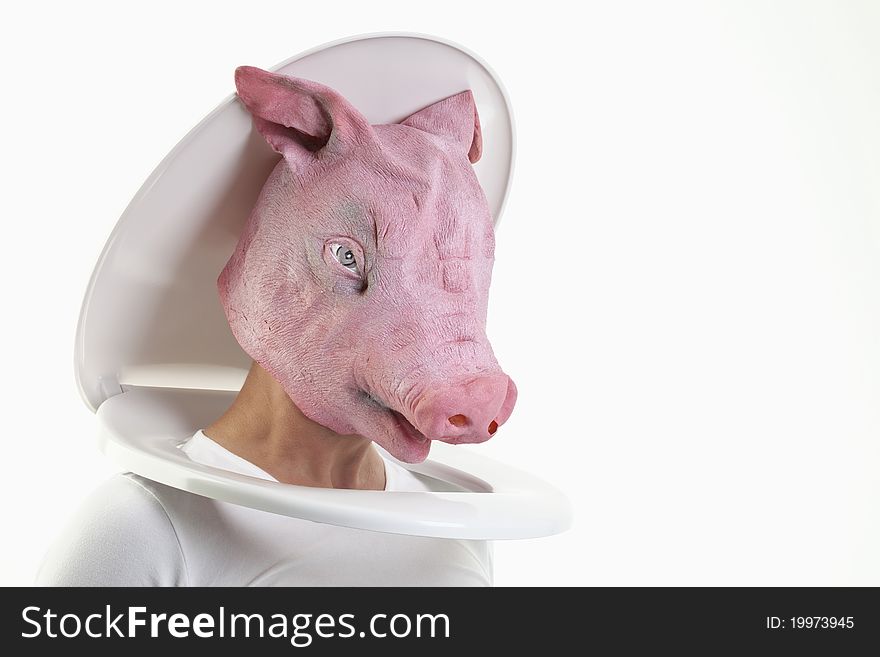 Man with a pig-mask puts his head through a toilet seat. Man with a pig-mask puts his head through a toilet seat