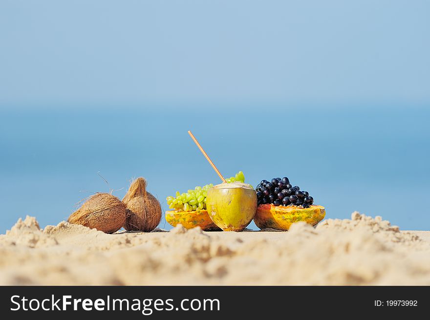 Papaya, coconut and grapes on the sandy beach. Papaya, coconut and grapes on the sandy beach