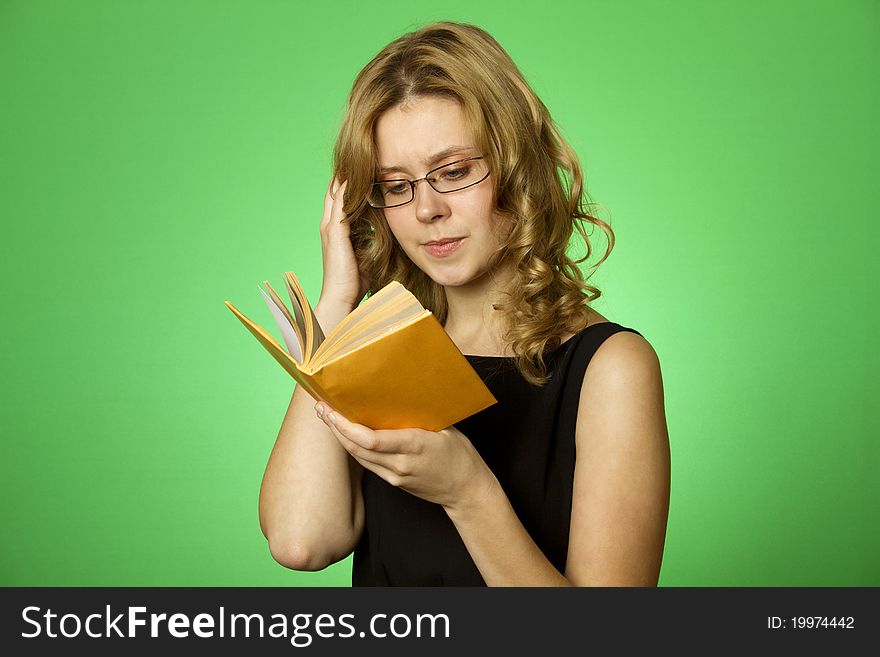 Close-up on a green background attractive girl with glasses and a little yellow book. Close-up on a green background attractive girl with glasses and a little yellow book