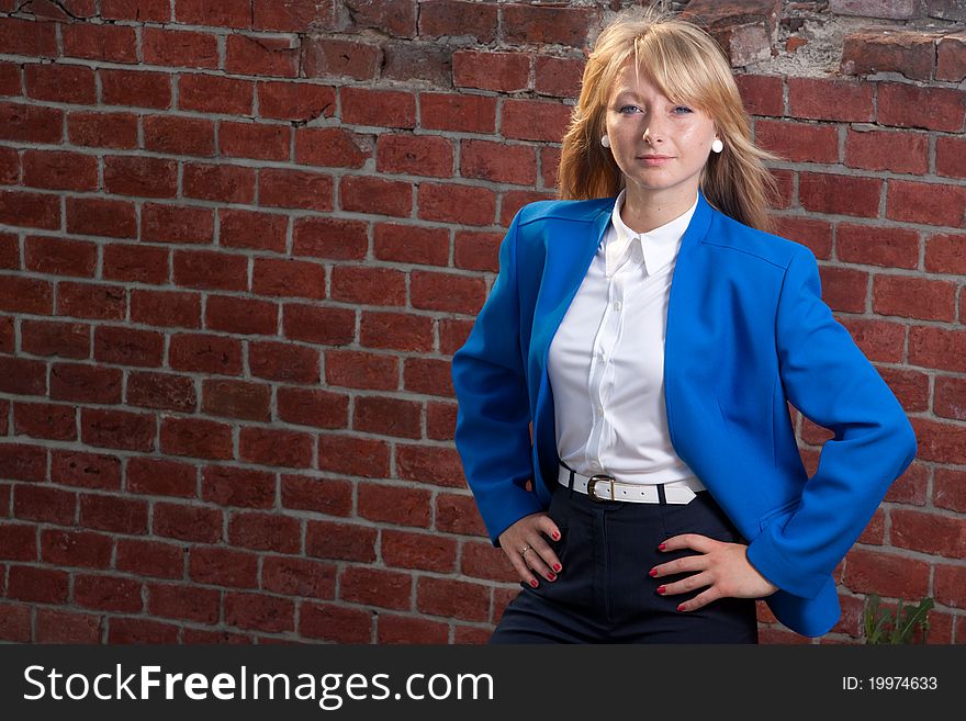 Blond elegant Woman sunlit from behind on background from red bricks. Blond elegant Woman sunlit from behind on background from red bricks