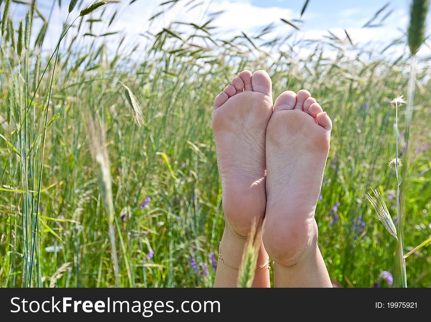 Woman two legs in green grass field under blue sky in summer