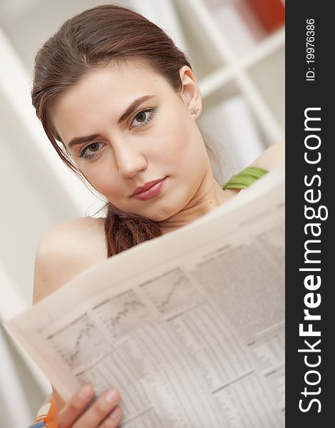 Young relaxed woman sitting on sofa with financial newspaper. Young relaxed woman sitting on sofa with financial newspaper