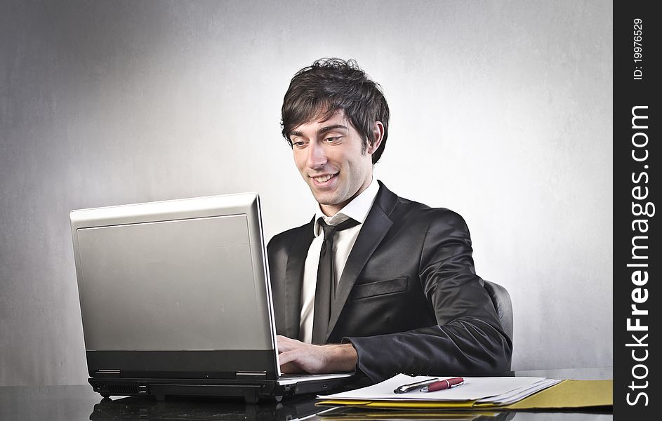 Smiling young businessman using a laptop. Smiling young businessman using a laptop