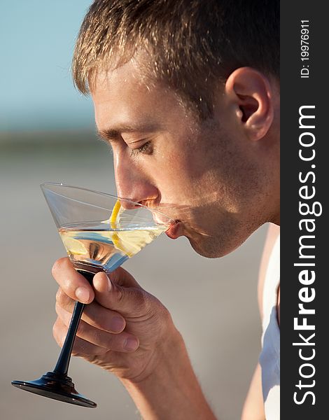 Portrait of guy drinking cocktail on beach