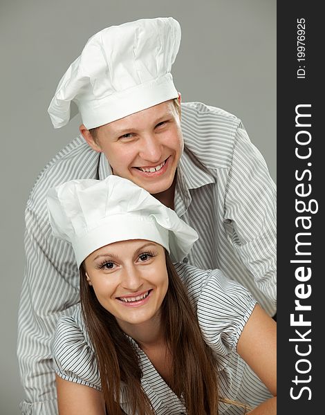 Young loving couple cooks. Over gray background