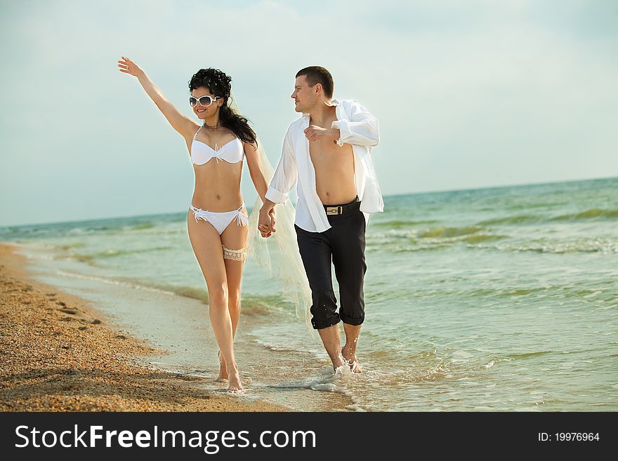 Bride and groom running in sunshine on a beautiful tropical beach. Bride and groom running in sunshine on a beautiful tropical beach