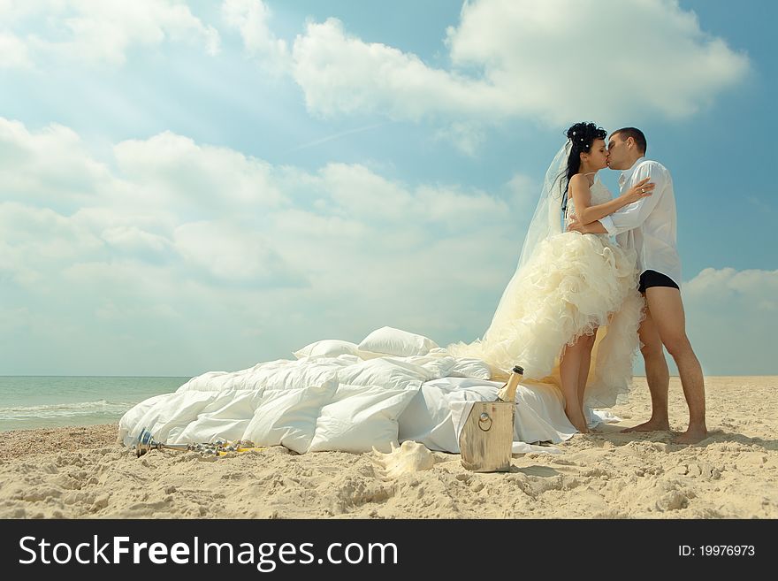 Bride and groom kissing next to bed on the beach. Bride and groom kissing next to bed on the beach