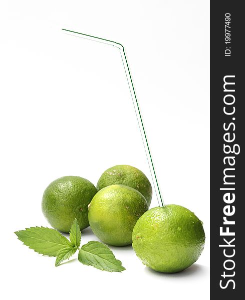 A lime with a drinking straw and fresh mint. A lime with a drinking straw and fresh mint