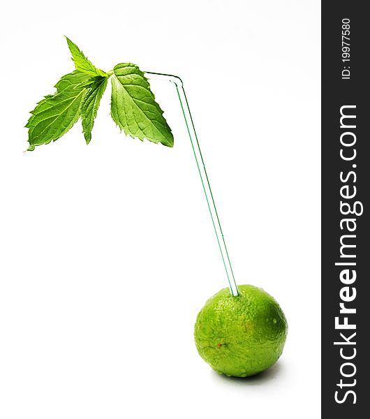 A lime with a drinking straw and fresh mint. A lime with a drinking straw and fresh mint