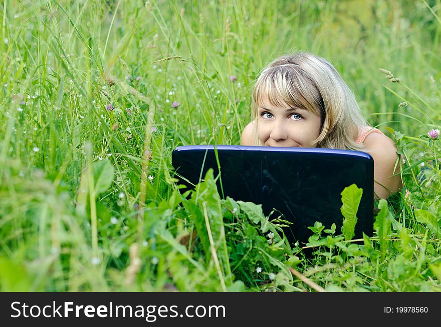 Young woman with a laptop on the grass