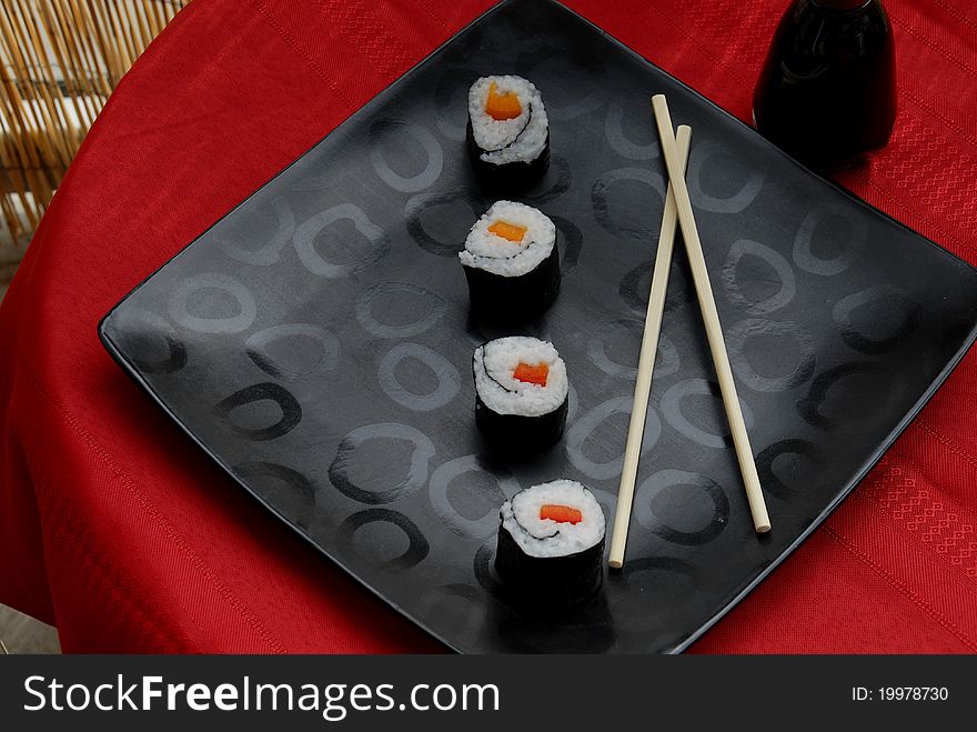 Four sushi rolls placed diagonally on a black plate. Four sushi rolls placed diagonally on a black plate