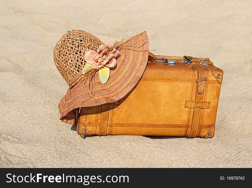 Suitcase and straw hat on rest on a seashore. Suitcase and straw hat on rest on a seashore