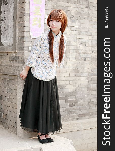 Chinese girl in traditional dress outdoor . Chinese characters on couplet is luck come. Chinese girl in traditional dress outdoor . Chinese characters on couplet is luck come.