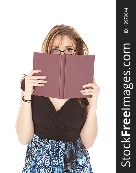 A woman peeking over the top of her book while she is wearing glasses. A woman peeking over the top of her book while she is wearing glasses.