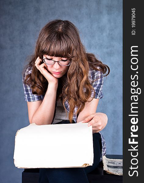Girl in glasses sitting and reading newspaper. Girl in glasses sitting and reading newspaper