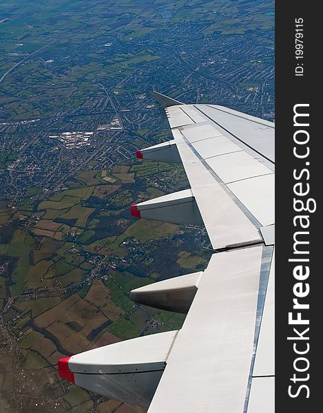 Airplane wing detail, flying over countryside, vertical composition. Airplane wing detail, flying over countryside, vertical composition